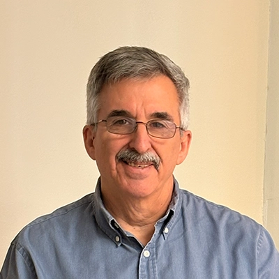 Chiropractor David Harnois Smiling In Front Of Off-White Wall